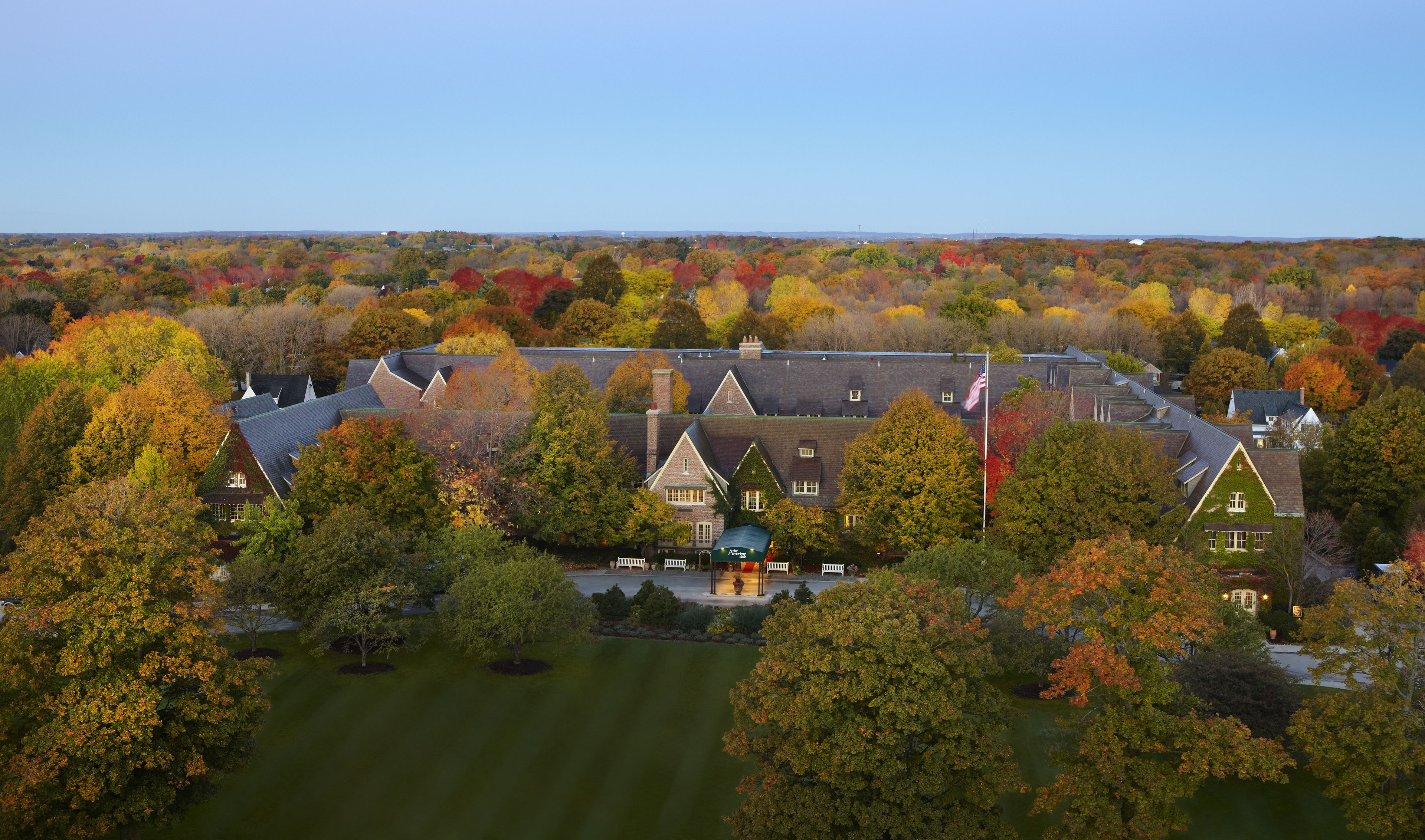 A large estate with multiple buildings, surrounded by a variety of trees in autumn colors.