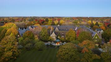 A large estate with multiple buildings, surrounded by a variety of trees in autumn colors.