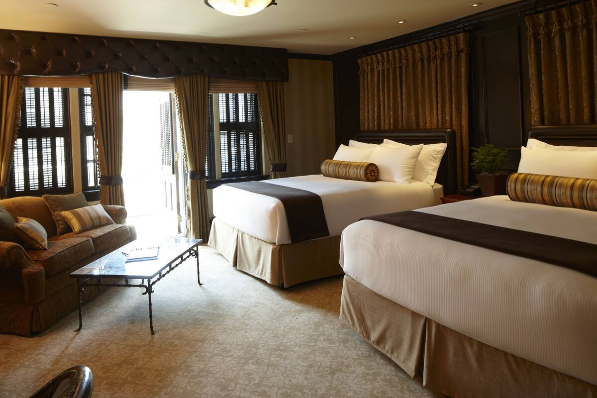 A hotel room with two beds, a sofa, a coffee table, and curtains.
