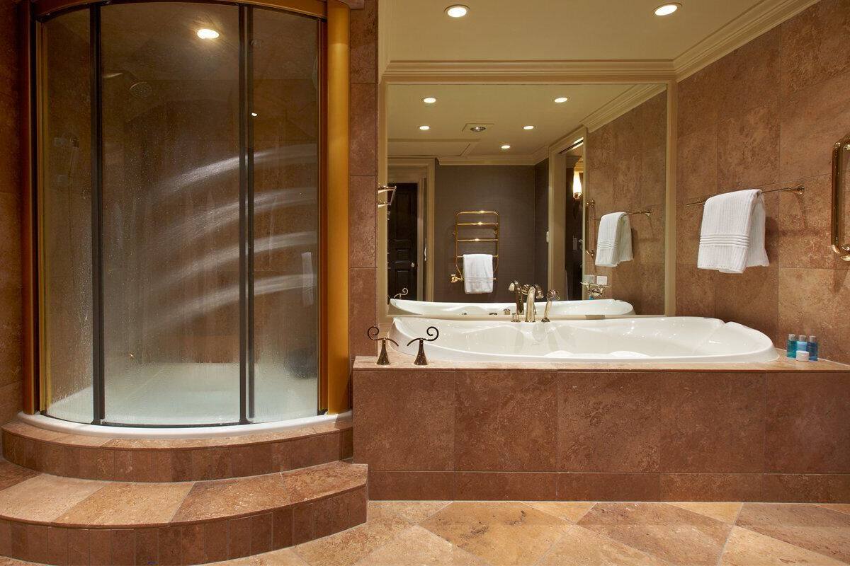 A luxurious bathroom with a glass-enclosed shower, a double sink vanity, and a large mirror.