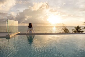 A woman sitting by a pool with a sunset view. - Angsana Laguna Phuket (Choeng Thale)