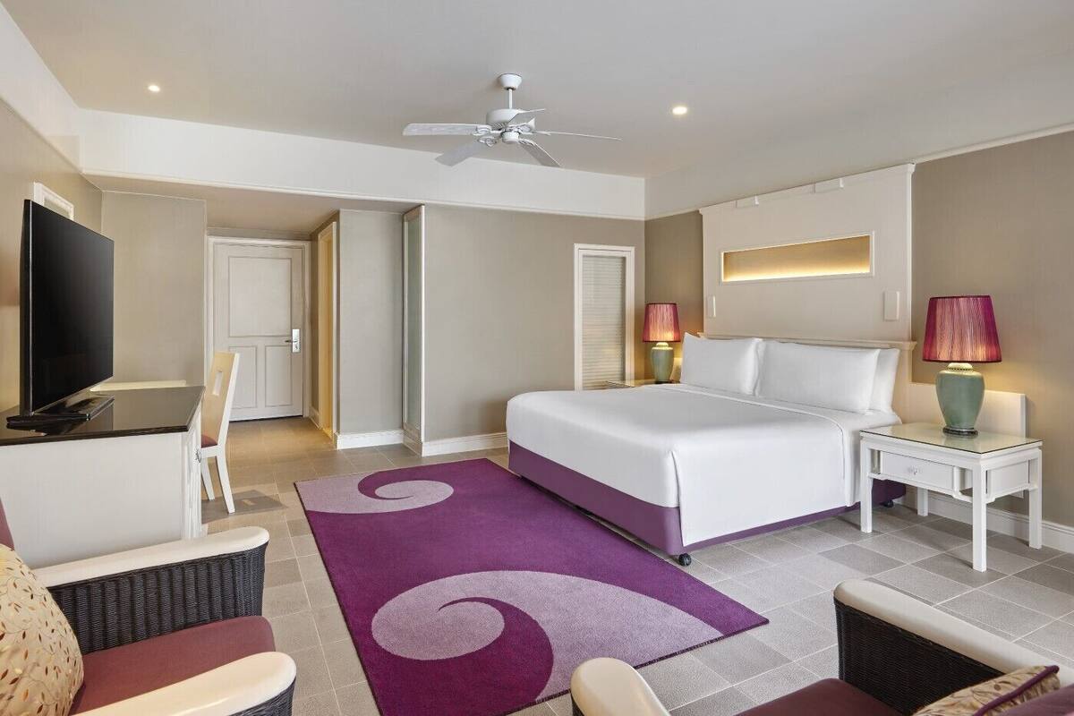 A hotel room with a bed, a TV, a desk, and a chair.