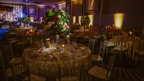 A banquet hall with round tables set for a formal event, featuring floral centerpieces and elegant table settings. - Wyndham Houston at Reliant Park & Medical Center (Houston)