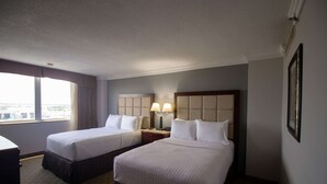 A hotel room with two beds, a nightstand with lamps, a window with curtains, and a framed picture on the wall. - Wyndham Houston at Reliant Park & Medical Center (Houston)