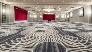 A spacious hall with a patterned carpet, a red curtain backdrop, and a grand chandelier. - Wyndham Houston at Reliant Park & Medical Center (Houston)