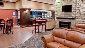 A lobby with a bar area, leather seating, and a stone wall. - Wyndham Houston at Reliant Park & Medical Center (Houston)