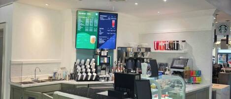 Café com balcão, cardápio e vitrine de doces.