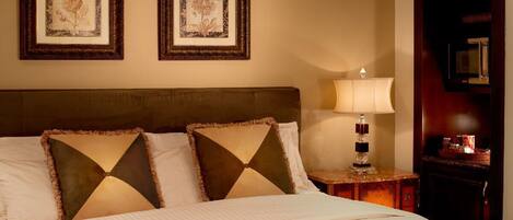 A neatly made bed with two pillows, a bedside lamp, and two framed pictures on the wall.