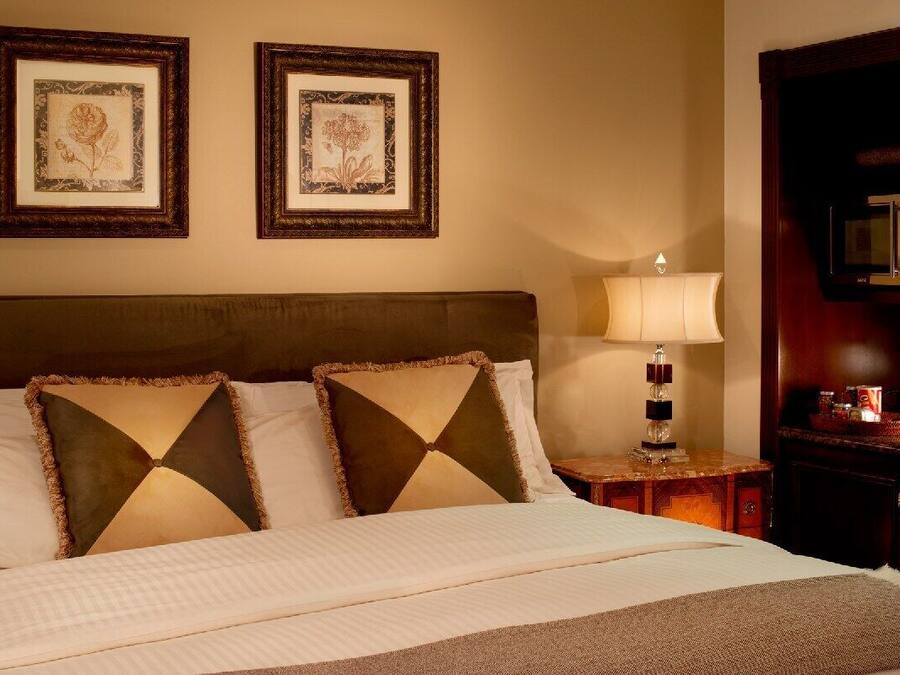 A neatly made bed with two pillows, a bedside lamp, and two framed pictures on the wall.