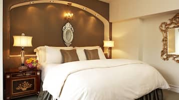 A hotel room with a large bed, two bedside lamps, a nightstand with a vase of flowers, and a mirror on the wall.