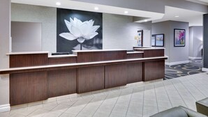 Un mostrador de recepción con un amplio mural floral, piso de baldosas y un cuadro en la pared.