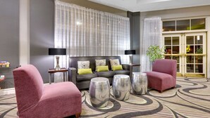Un hall de hotel con un sofá, dos sillones, una mesita de centro y una alfombra estampada.