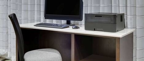A compact workspace with a monitor, keyboard, mouse, and printer on a white desk.