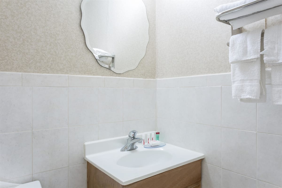 A bathroom with a white sink, a mirror, and a towel rack.