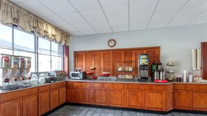 A kitchen with wooden cabinets, a coffee machine, a microwave, and a clock on the wall. - Ramada Limited Norfolk (Norfolk)