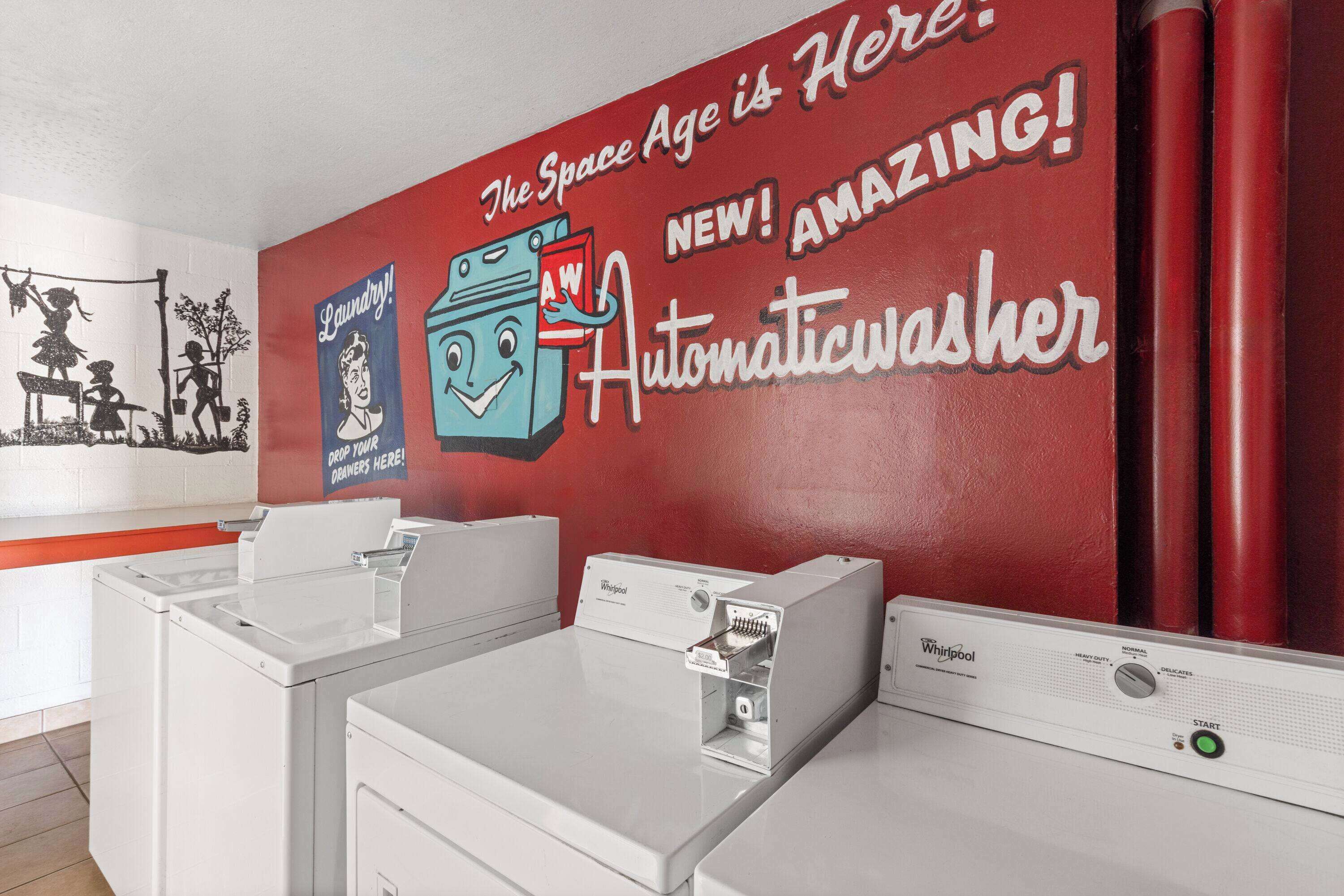 Una lavandería con una pared roja y un mural publicitario de una lavadora automática.