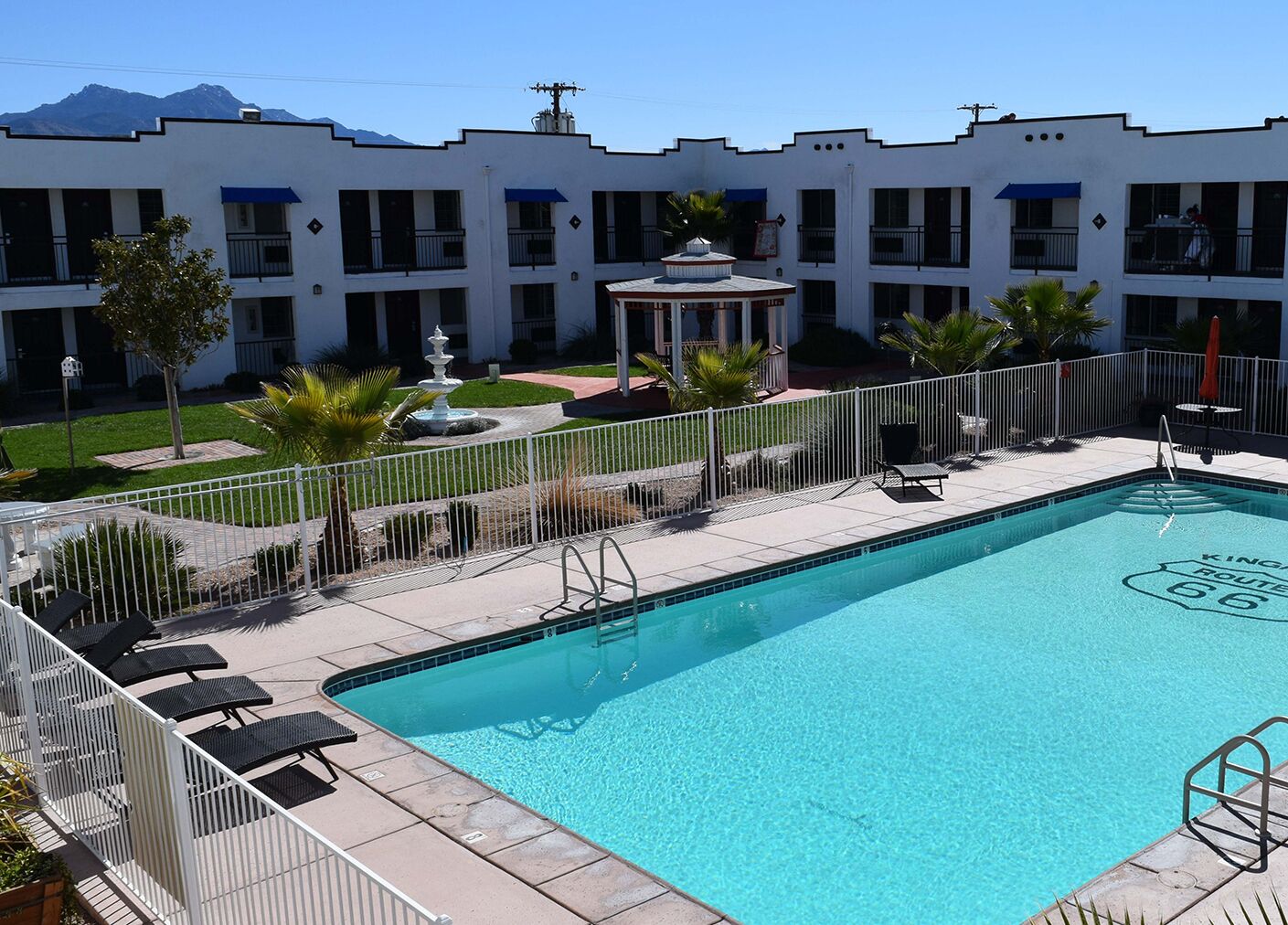 A pool area with a clear blue pool, lounge chairs, and a gazebo.