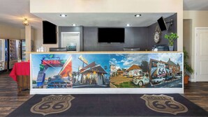 A reception desk with a Route 66 themed mural, a flat-screen TV, and a clock on the wall. - Ramada by Wyndham Kingman (Kingman)