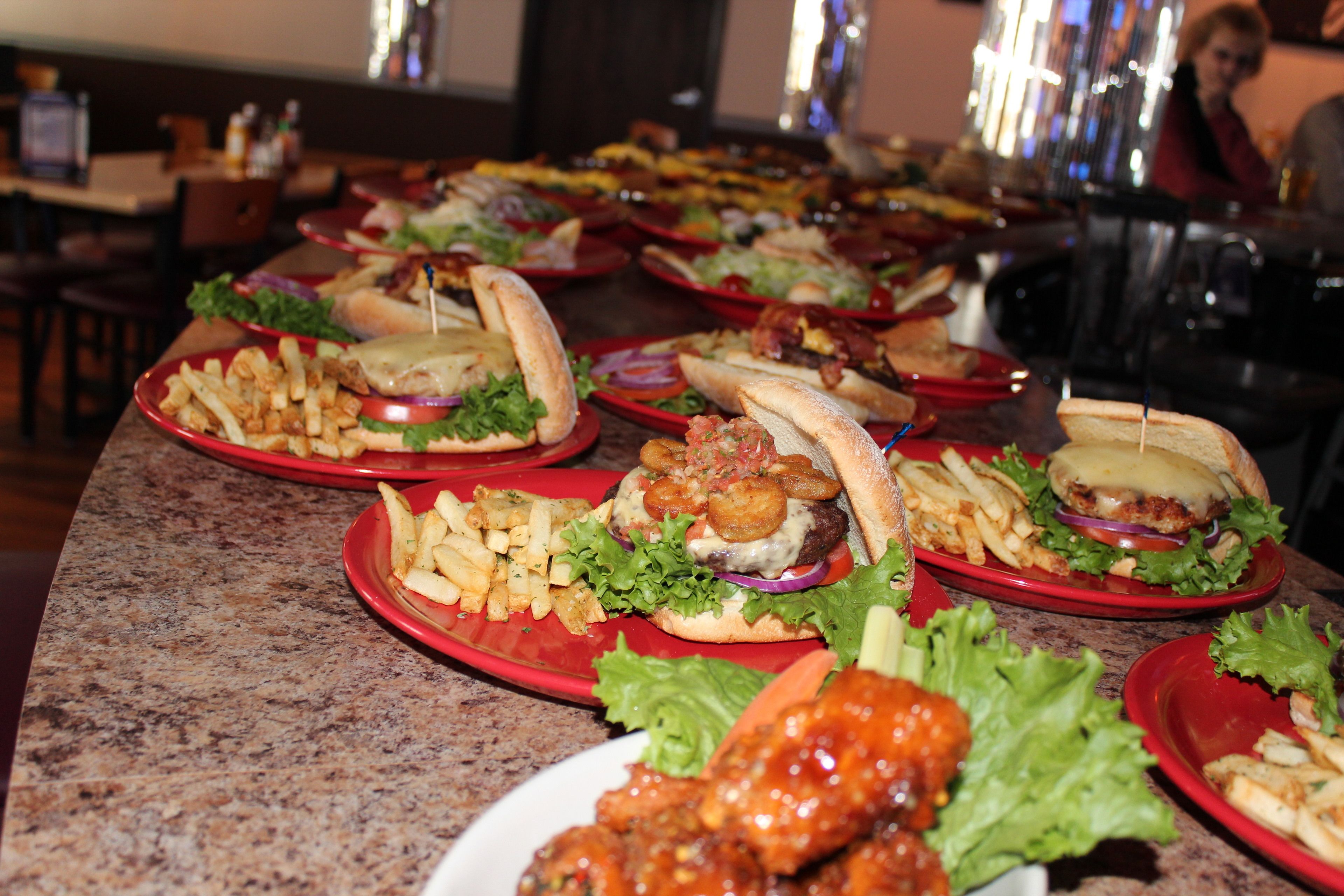 A buffet table with various food items including burgers, fries, and chicken wings.