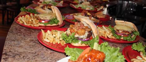 A buffet table with various food items including burgers, fries, and chicken wings.