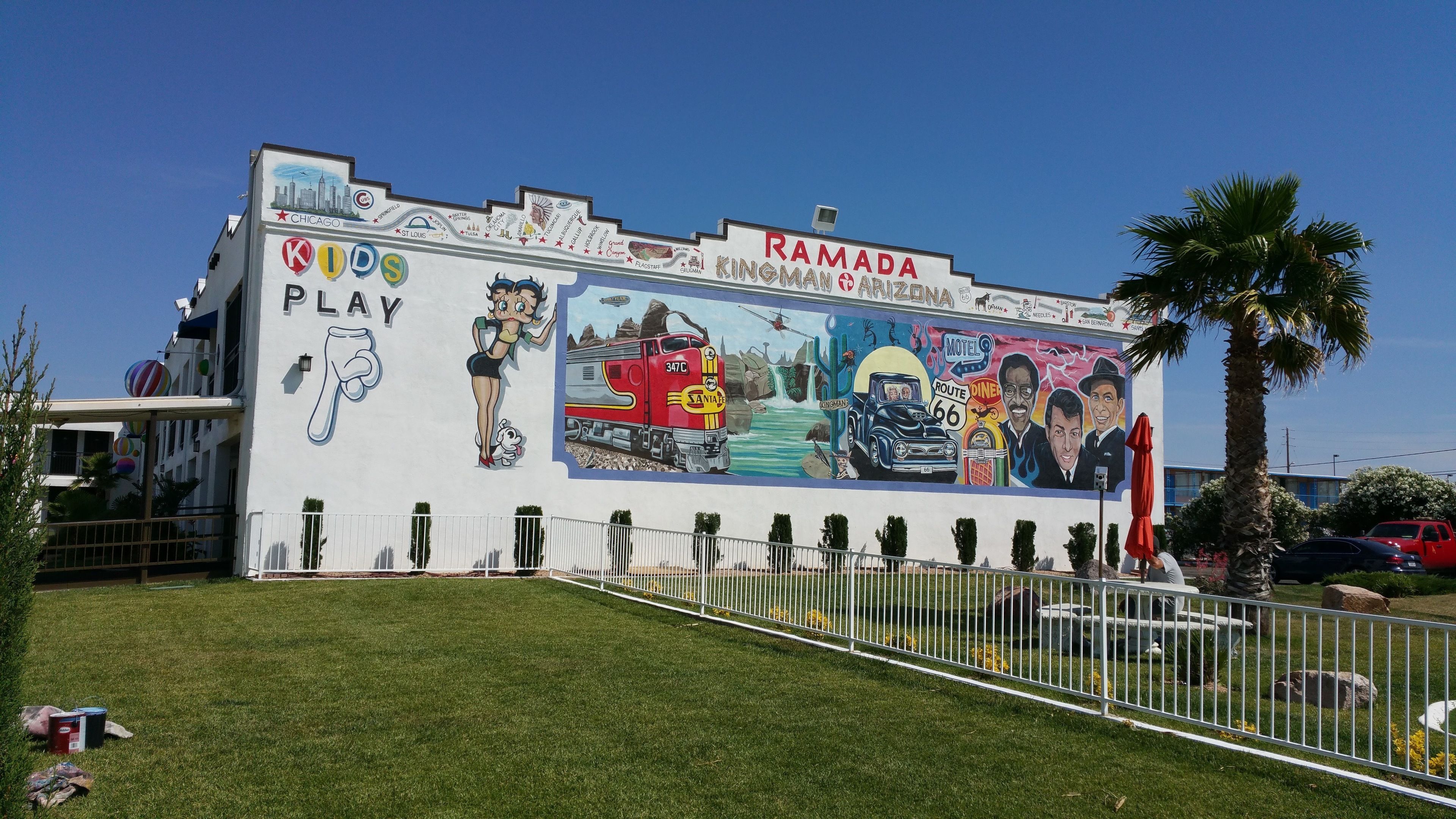 A building with a mural advertising Ramada Kingman & Arizona Motel, including a train, diner, and Route 66.