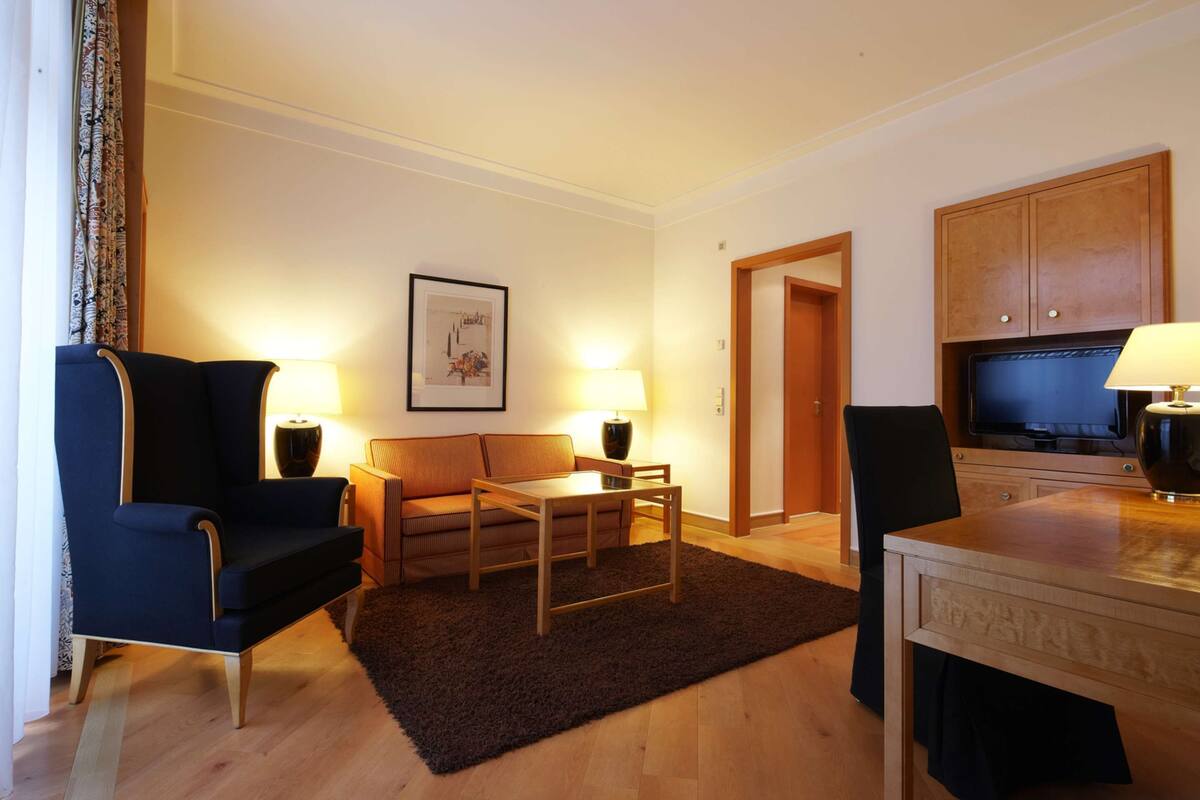 Une chambre d’hôtel avec un canapé, une petite table, une télévision et un meuble.