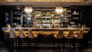 A bar area with a marble floor, bar stools, and a well-stocked liquor shelf. - The Westbury Hotel (Dublin)