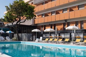 Una piscina al aire libre, sombrillas, tumbonas