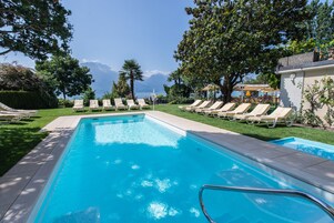 Piscina con sillones de descanso y vistas a montañas.