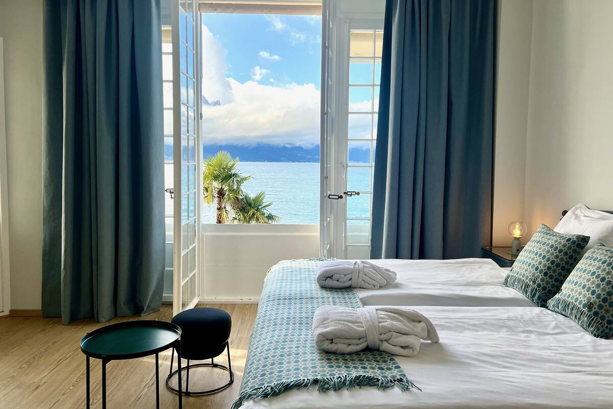 Habitación de hotel con una cama grande, una mesita y vista al mar.