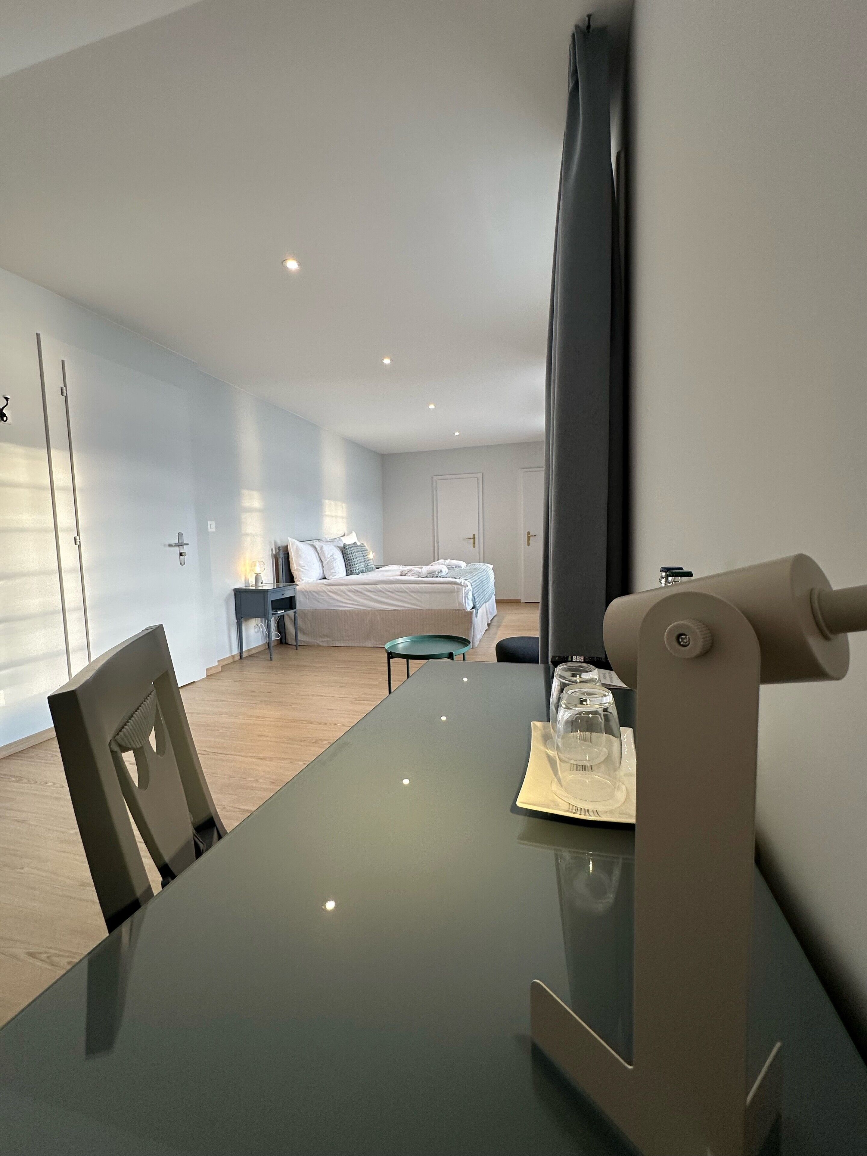 Una habitación de hotel moderna con una cama grande, un escritorio con computadora y una mesa de comedor.