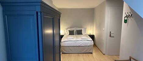 Un dormitorio con cama, armario y suelo de madera.