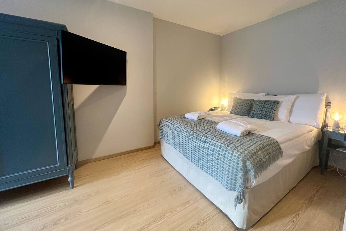 Un dormitorio con cama, lámparas de noche, armario y televisor de pantalla plana montado en la pared.
