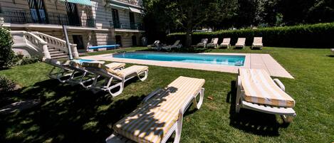 A pool area with lounge chairs and a staircase leading to a building.