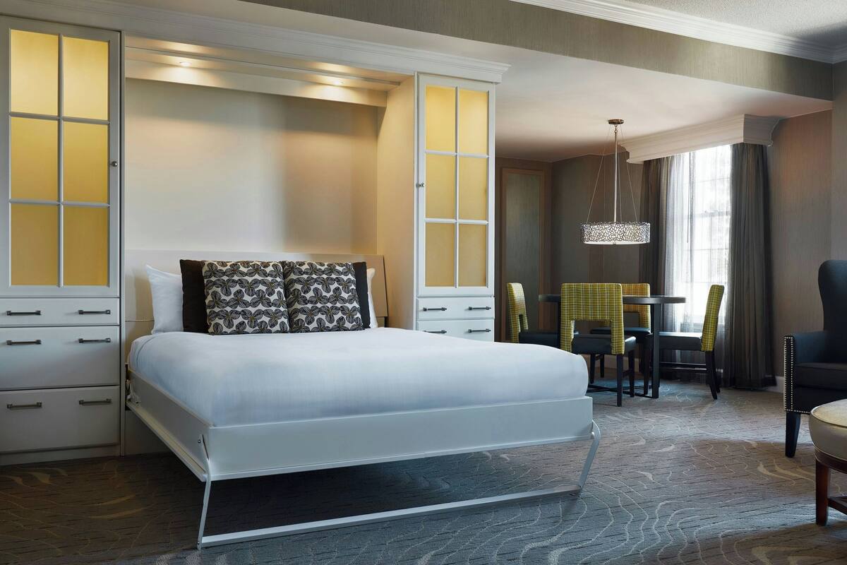 Une chambre d’hôtel avec un lit, un bureau et une chaise.