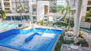 Zona de piscina interior con varios niveles, diferentes opciones de asientos y una fuente central.