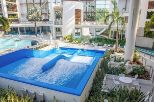 A multi-level indoor pool area with various seating arrangements and a central water feature.