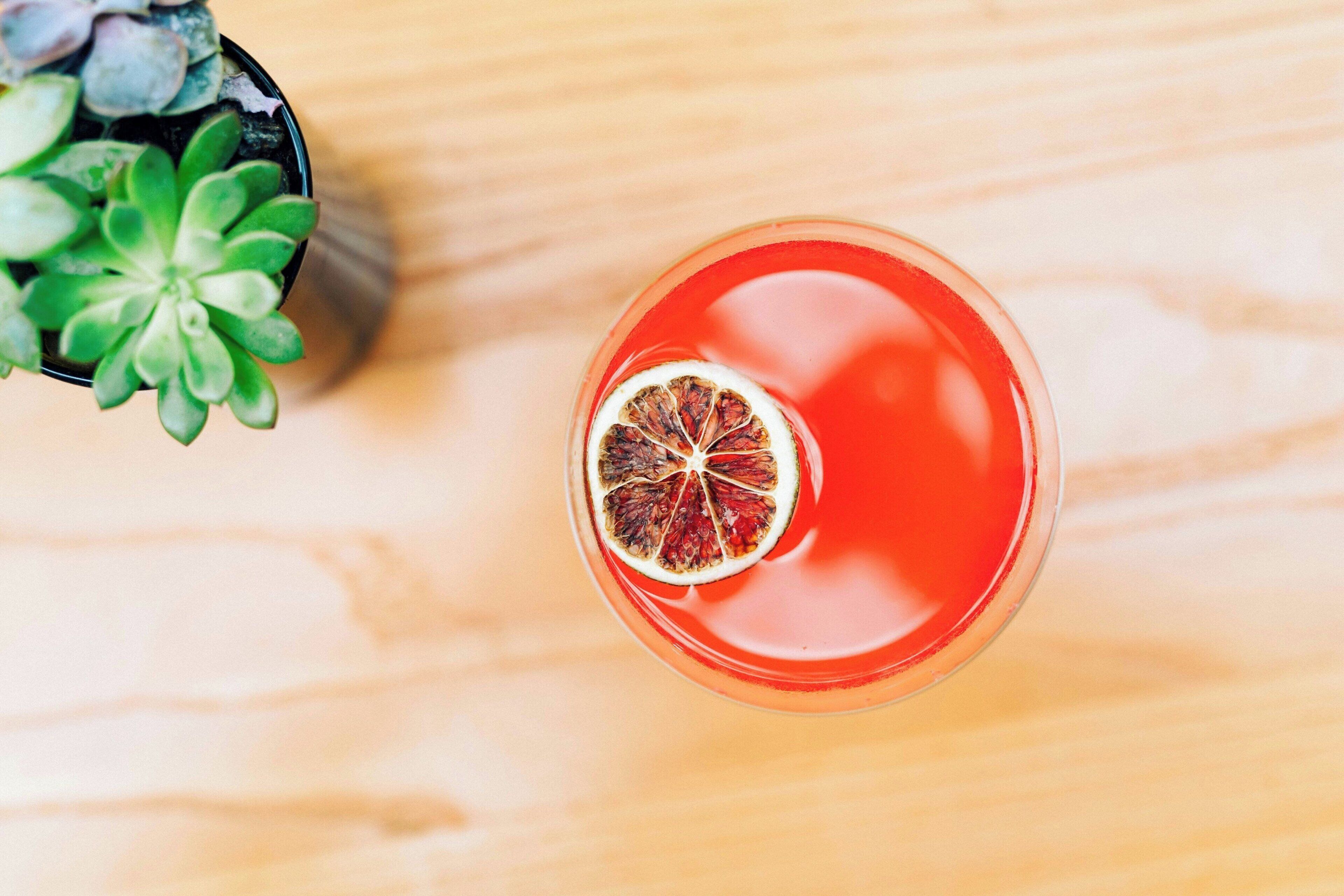 A top-down view of a red drink with a dried fruit garnish on a wooden surface.