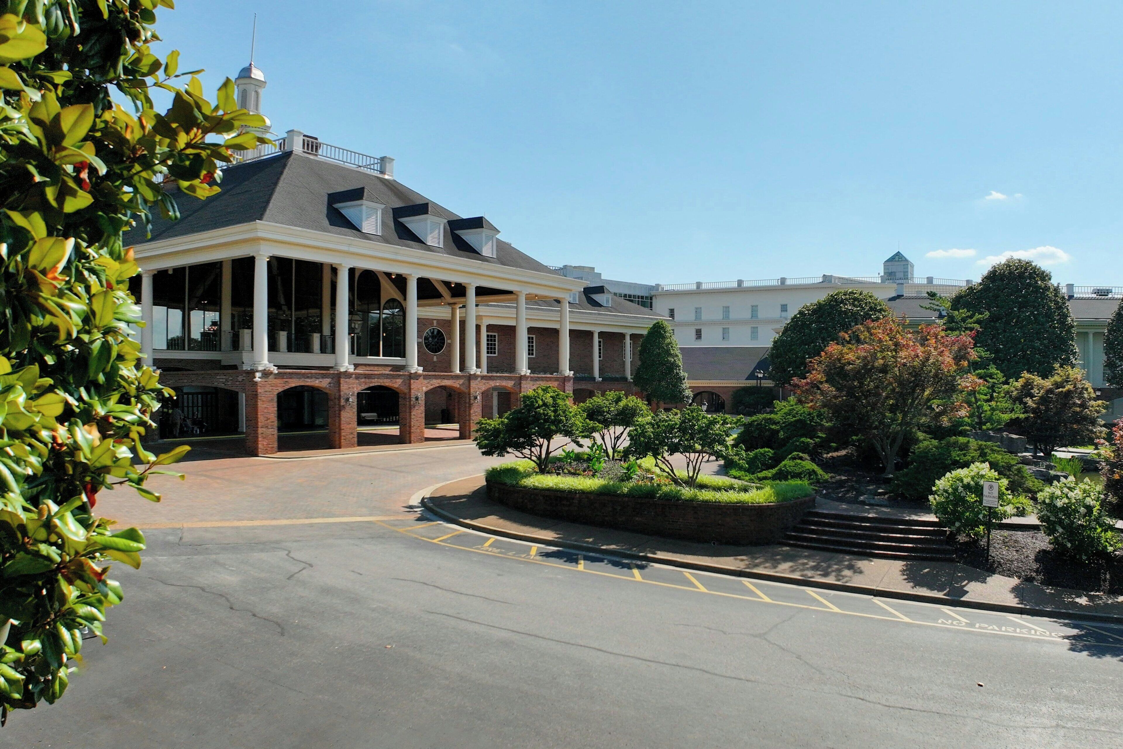 A building with a covered patio area, brick walls, and a landscaped garden with a fountain.