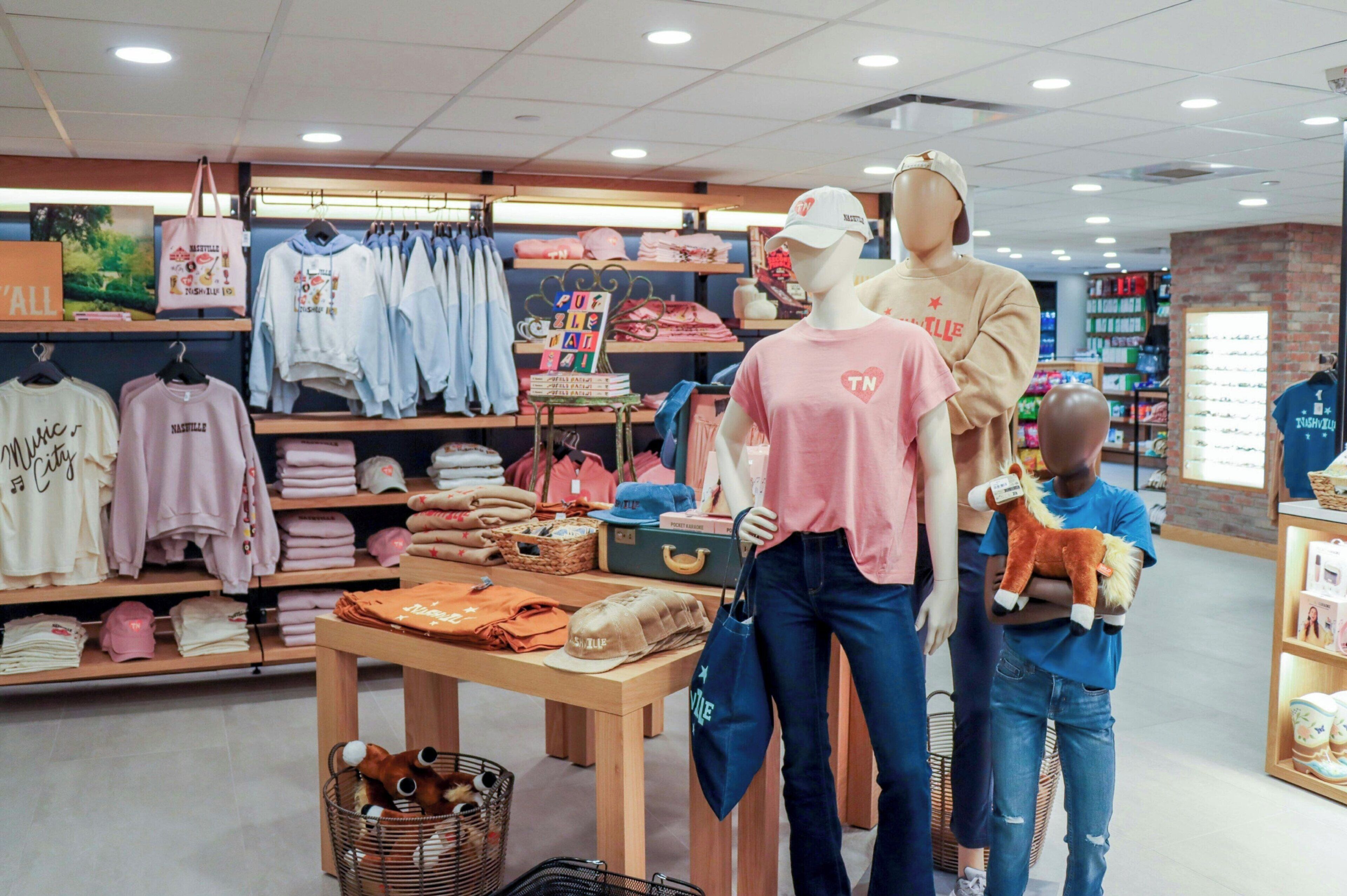 A clothing store with mannequins, shelves of folded clothes, and a table with items.