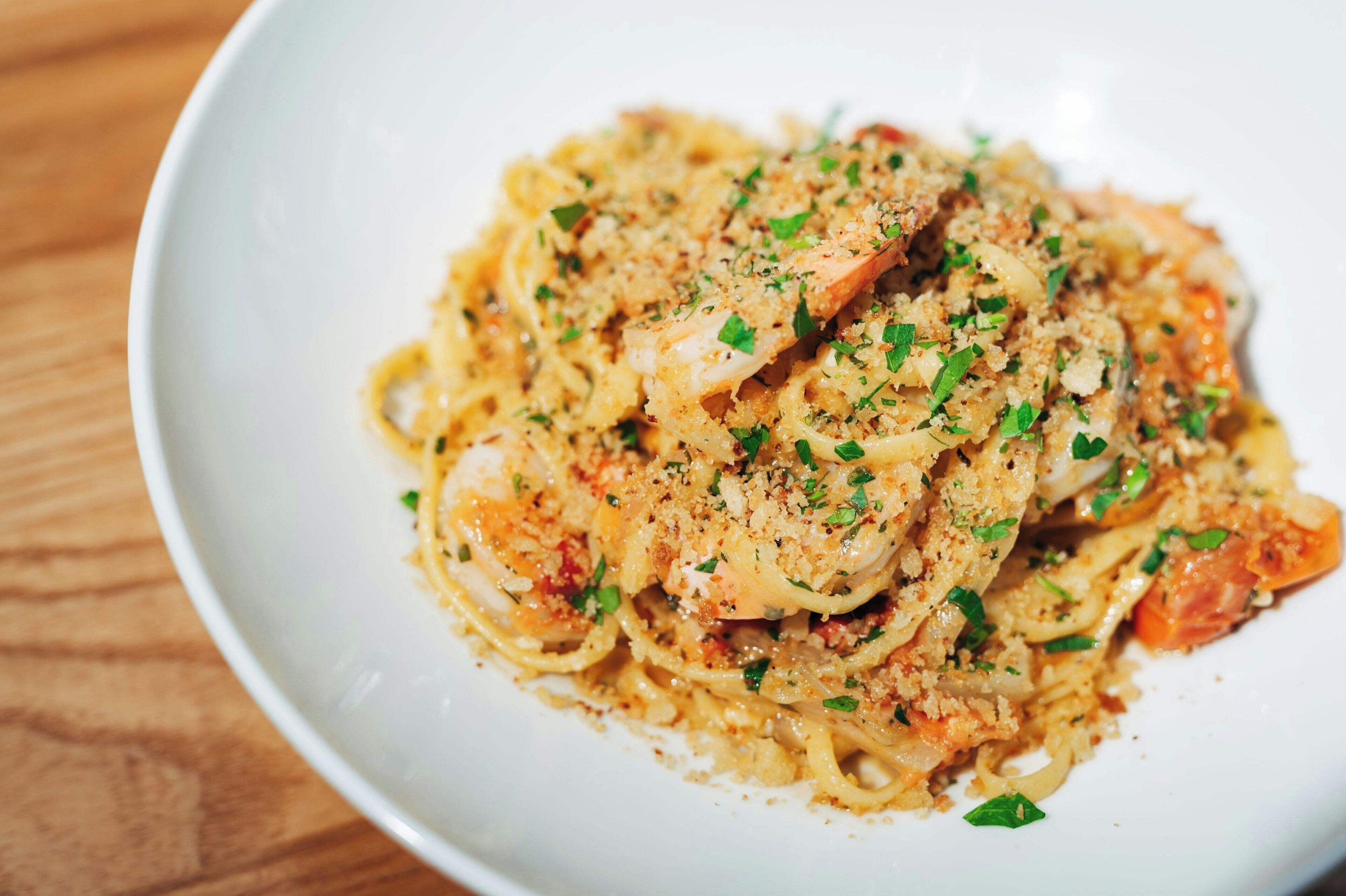 A plate of pasta with shrimp and a garnish of herbs.