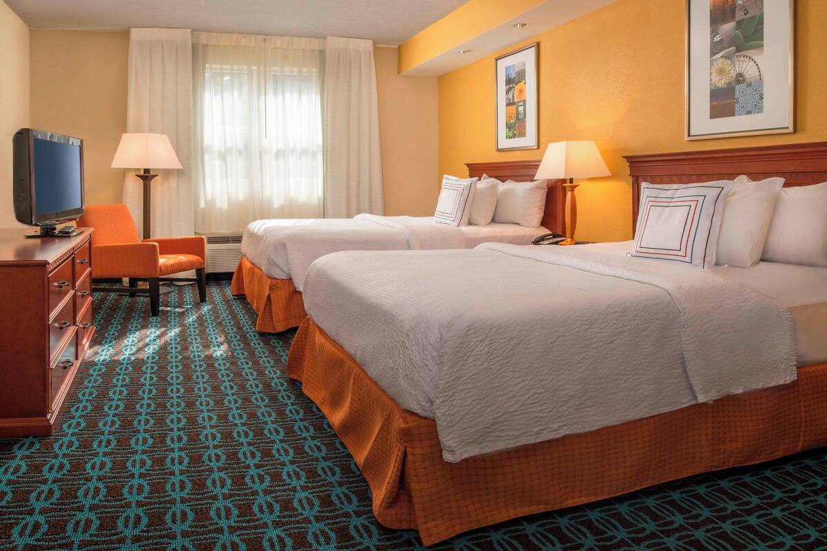 Une chambre d’hôtel avec deux lits, une télévision, un bureau et une chaise.