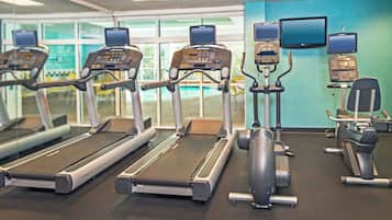 Un gimnasio con cintas de correr, elípticas y bicicletas estáticas.