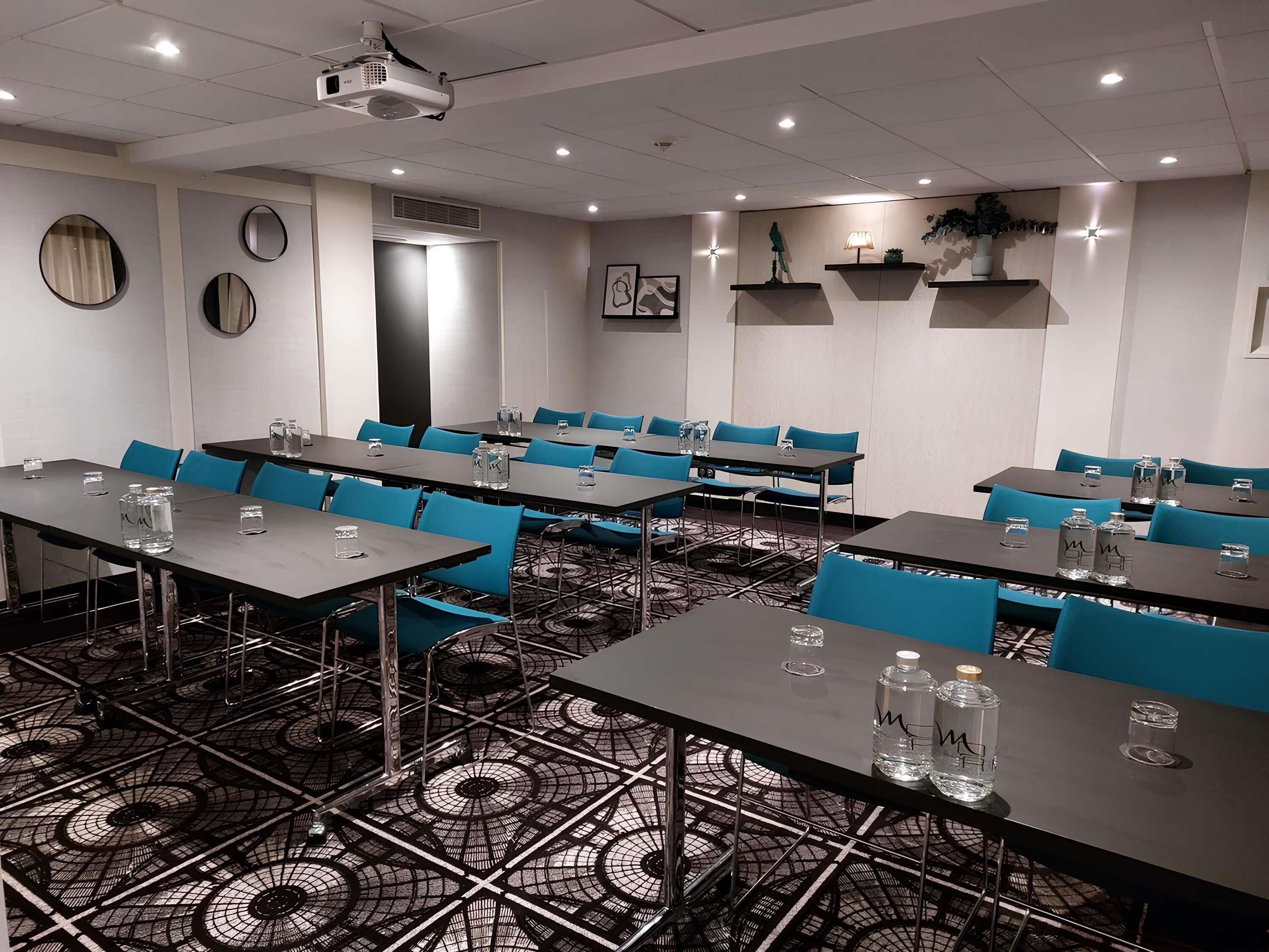 A conference room with tables, chairs, a projector, and a patterned floor.