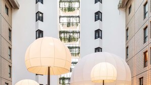 Un edificio moderno con grandes lámparas esféricas, un atrio central con plantas y múltiples ventanas.