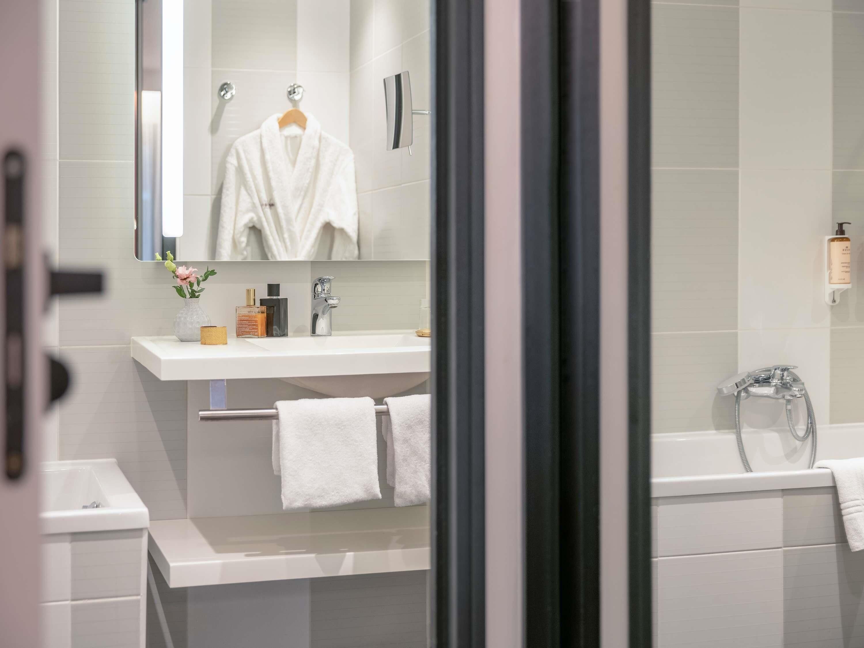 A modern bathroom with a white sink, mirror, and shower.