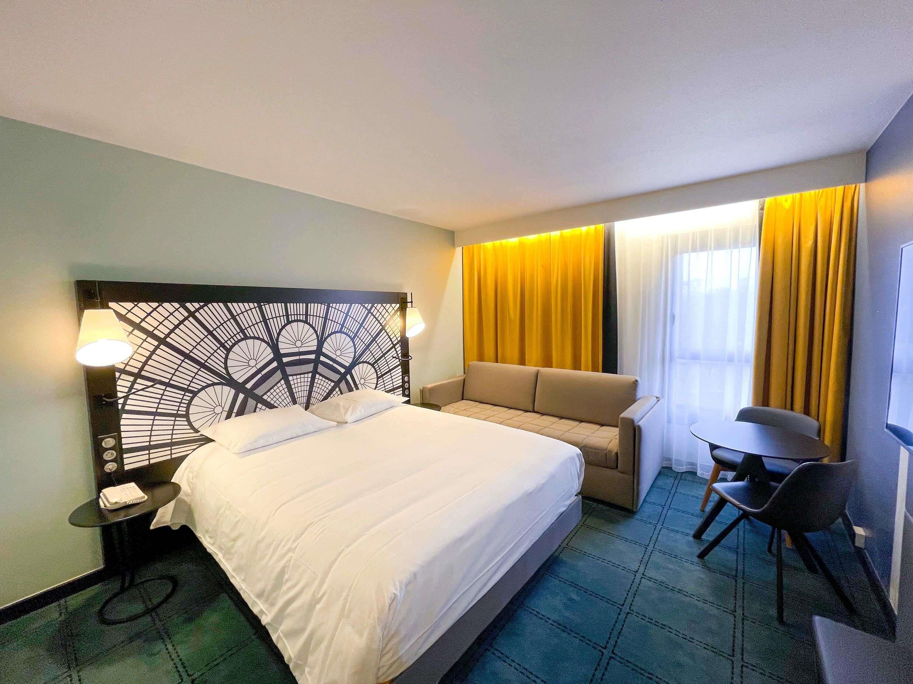 Ein Hotelzimmer mit Bett, einer Couch, einem Schreibtisch und einem Stuhl.