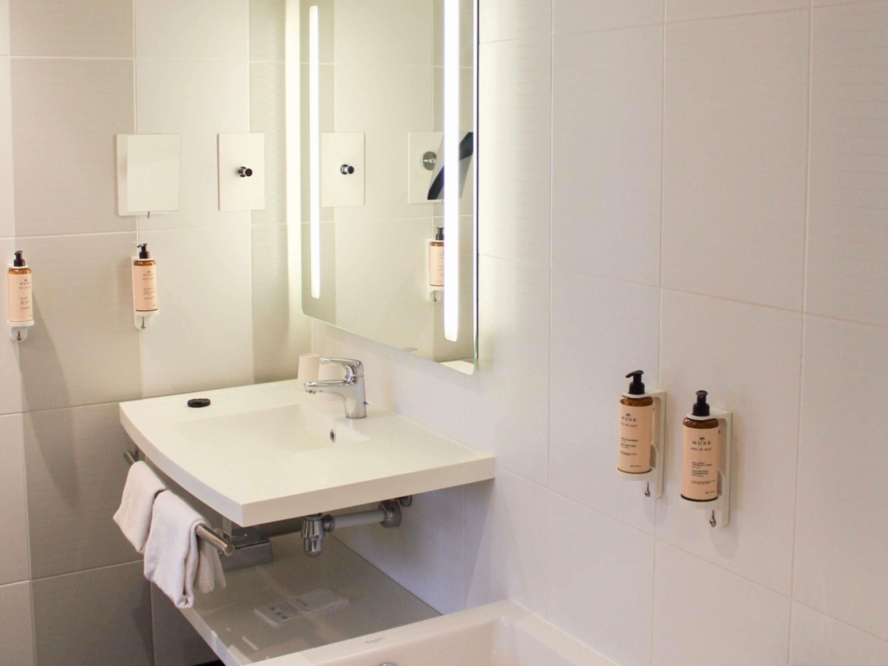 A bathroom with a white sink, mirror, and two hand sanitizer dispensers.