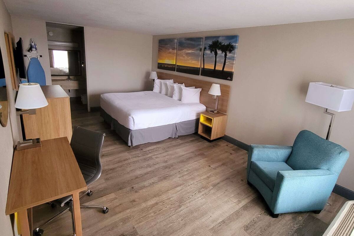 Ein Hotelzimmer mit Bett, Schreibtisch, Stuhl und einem Bild an der Wand.