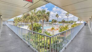 A covered outdoor area with a pool, palm trees, and a white railing. - Days Inn by Wyndham Titusville Kennedy Space Center (Titusville)